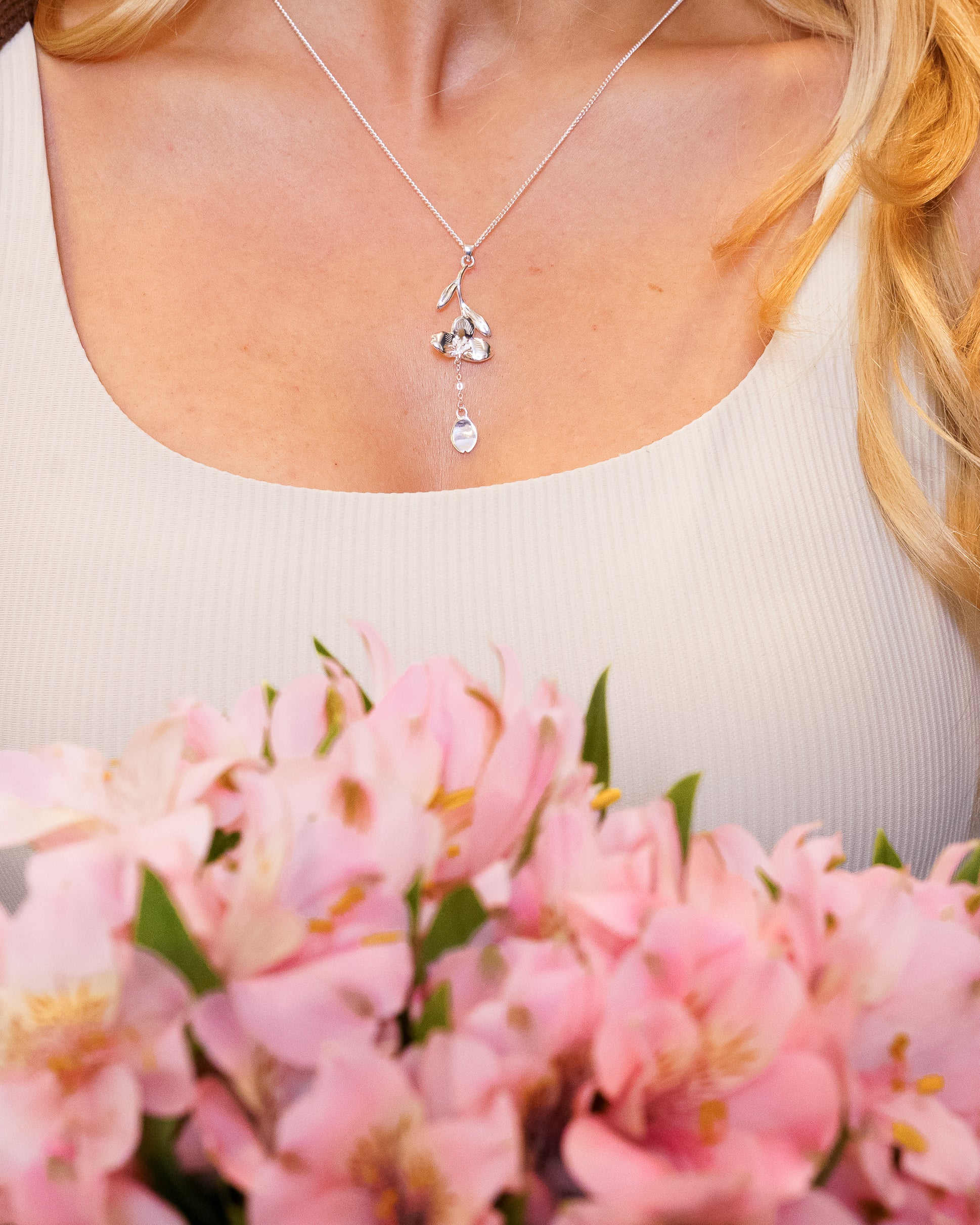 Woman wearing silver loves me not necklace around neck.