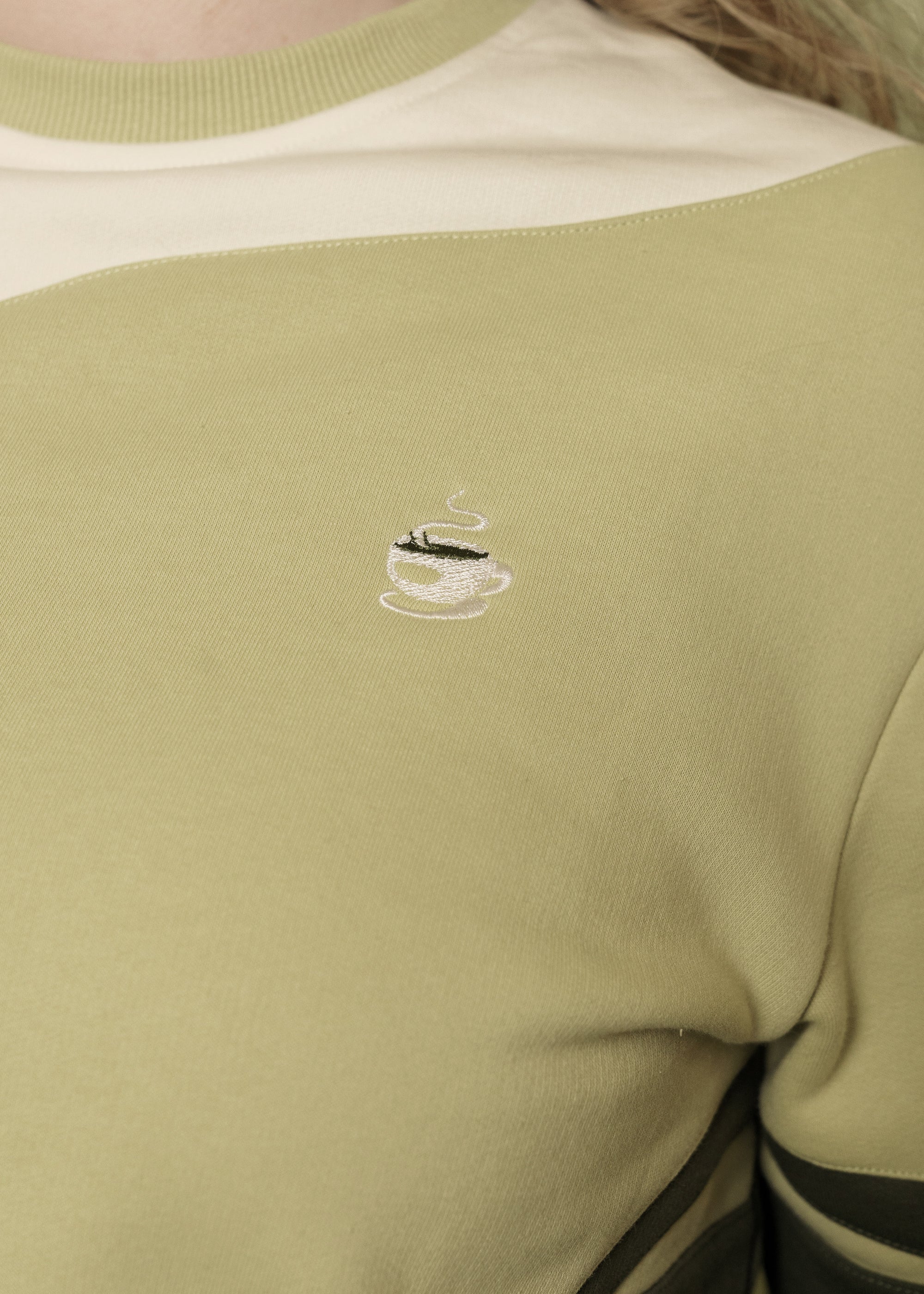 Close up of embroidered mug on front side of matcha crewneck.