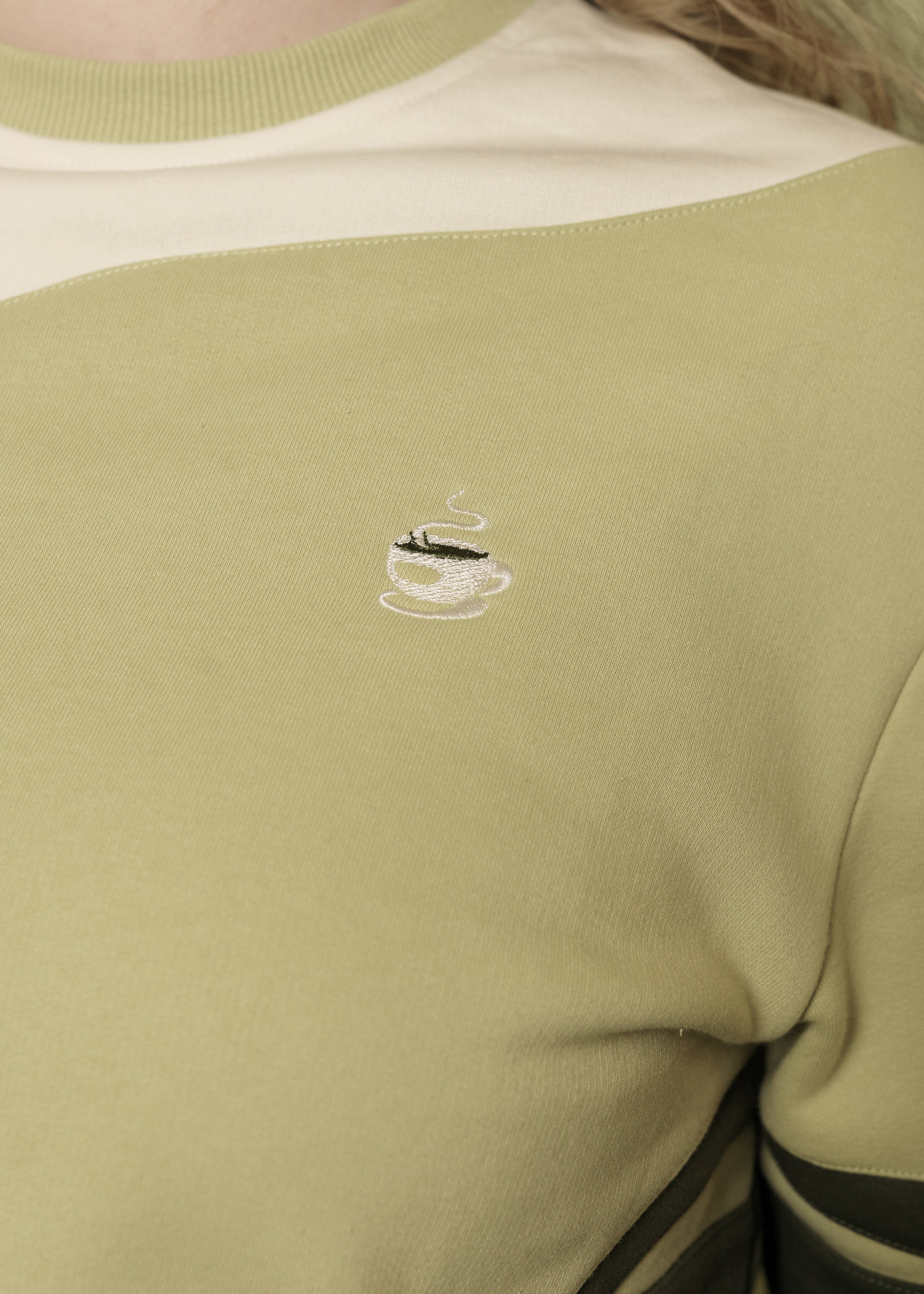 Close up of embroidered mug on front side of matcha crewneck.
