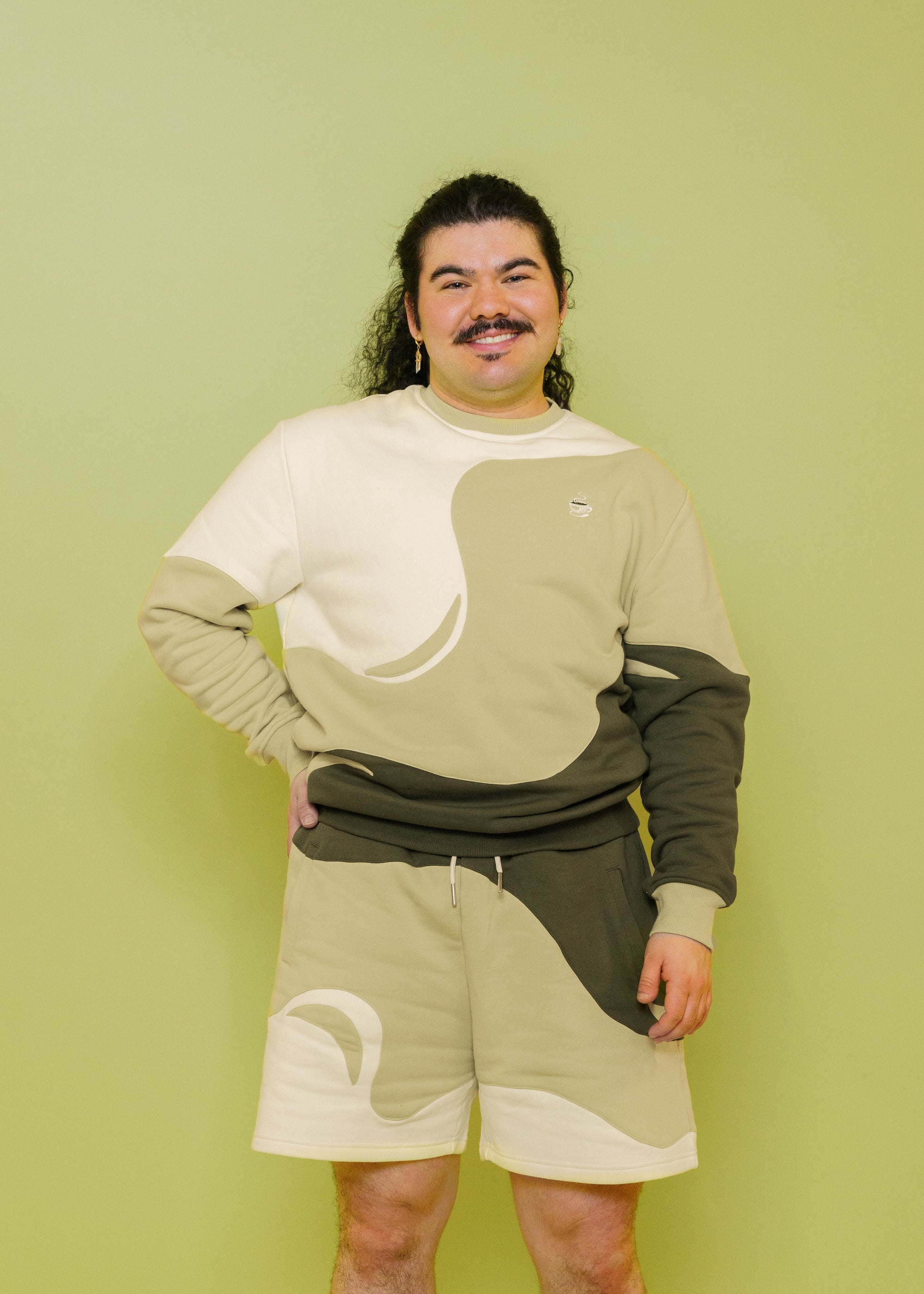 Man wearing monochromatic green matcha jogger shorts in size extra large with matcha crewneck in front of green background.