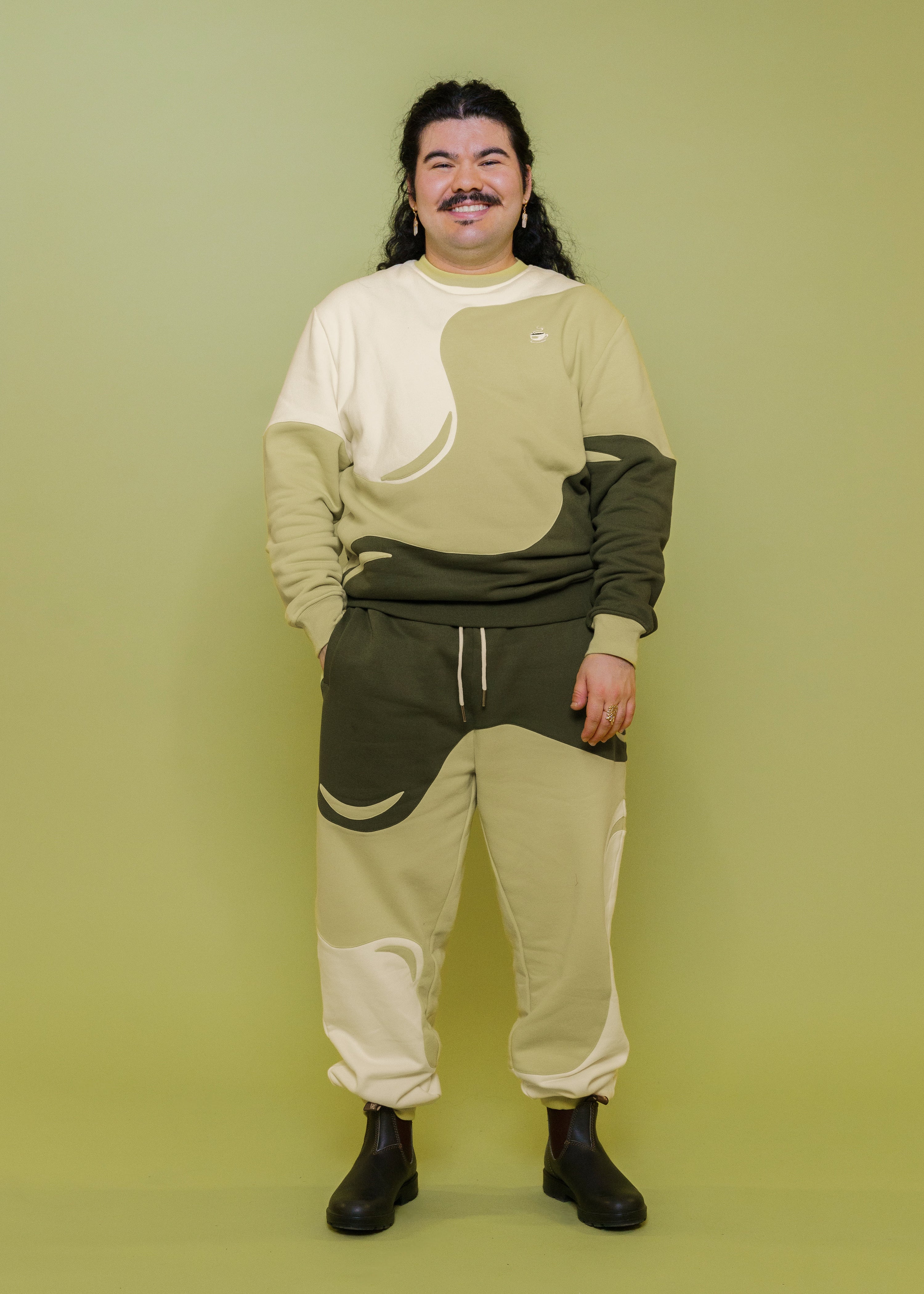 Man wearing monochromatic green matcha joggers in size extra large and matcha crewneck in front of green background.