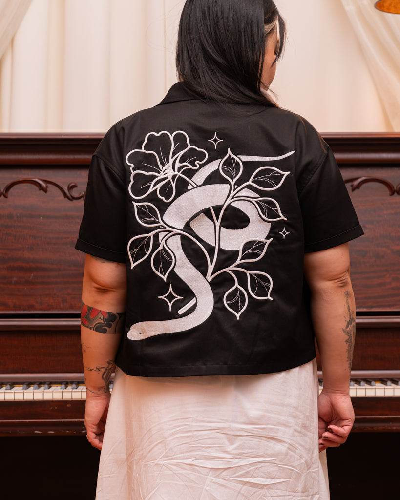 Back view of mysterious boxy over-shirt in size large showcasing snake and floral design embroidered in silver thread.
