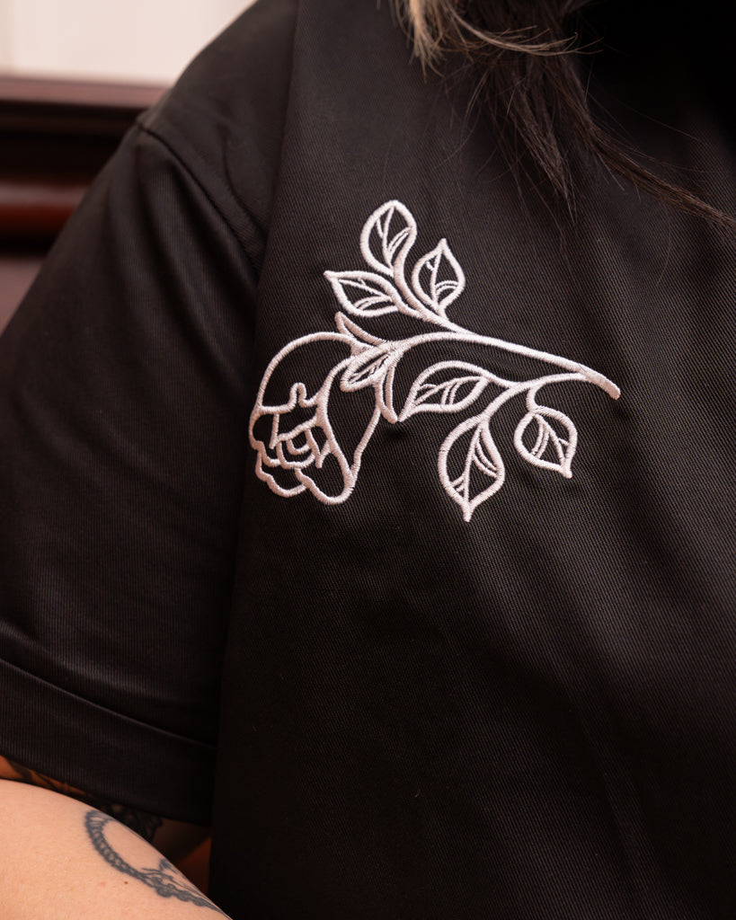 Close up of embroidered silver rose on front side of shirt.