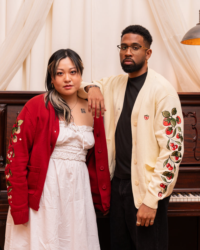 Man wearing strawberry cream cardigan in size large standing beside woman wearing berry blend cardigan.