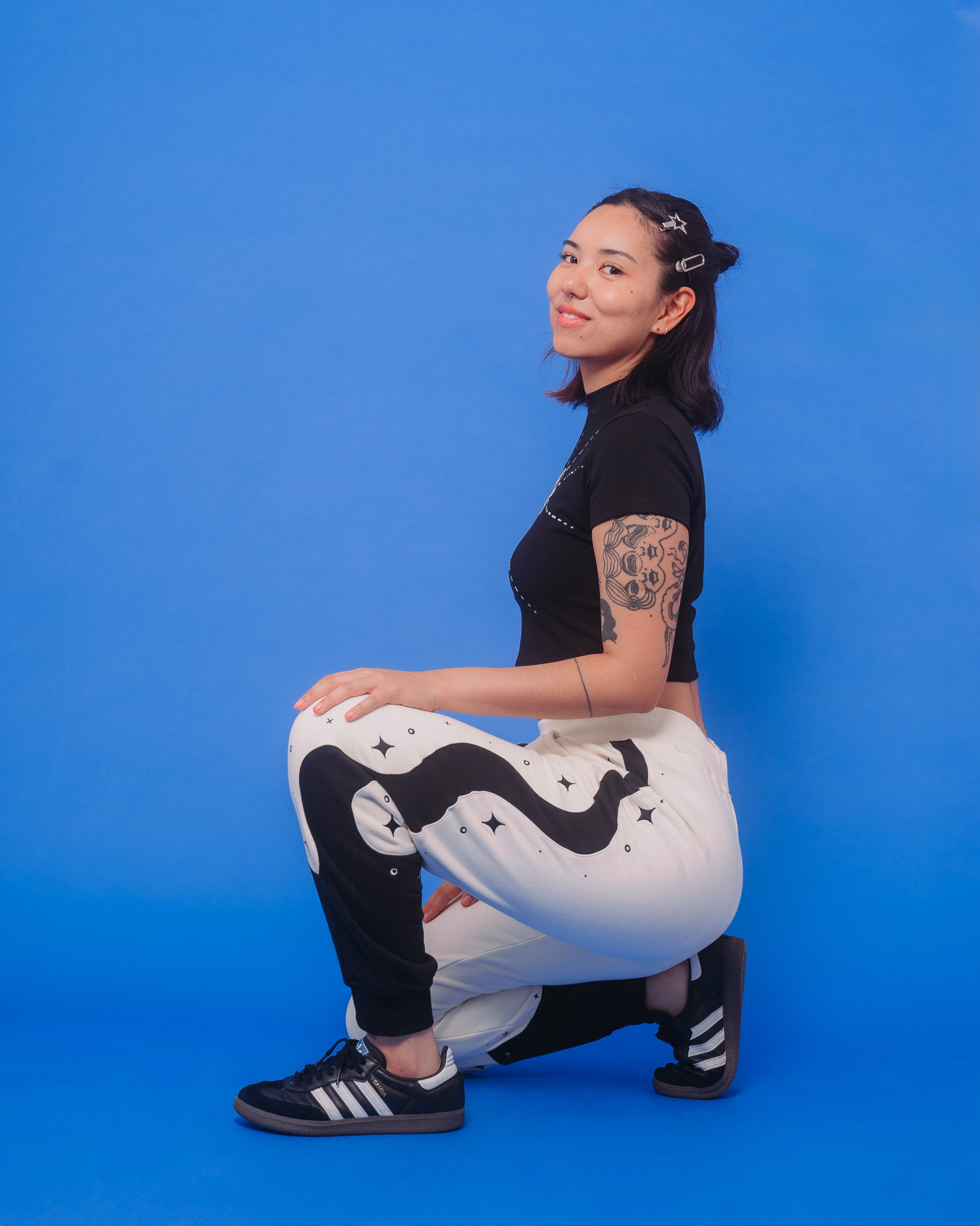 Woman wearing supernova joggers in size medium kneeling down in front of blue background.