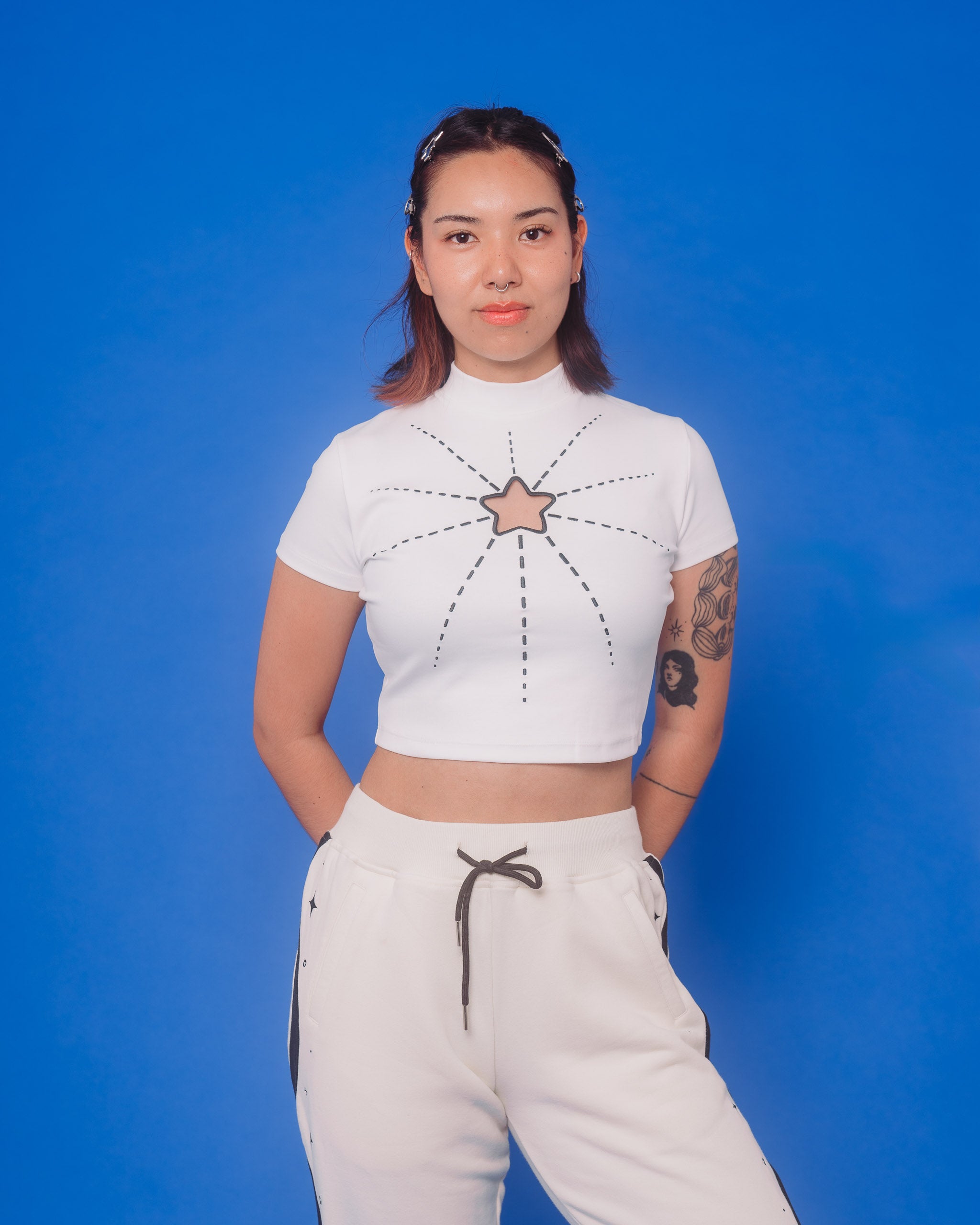 Woman wearing white supernova mini tee in size medium in front of blue background.