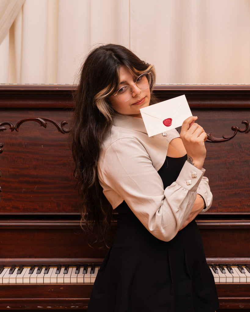 Woman wearing white sweetheart bolero shirt in size small holding a love letter.