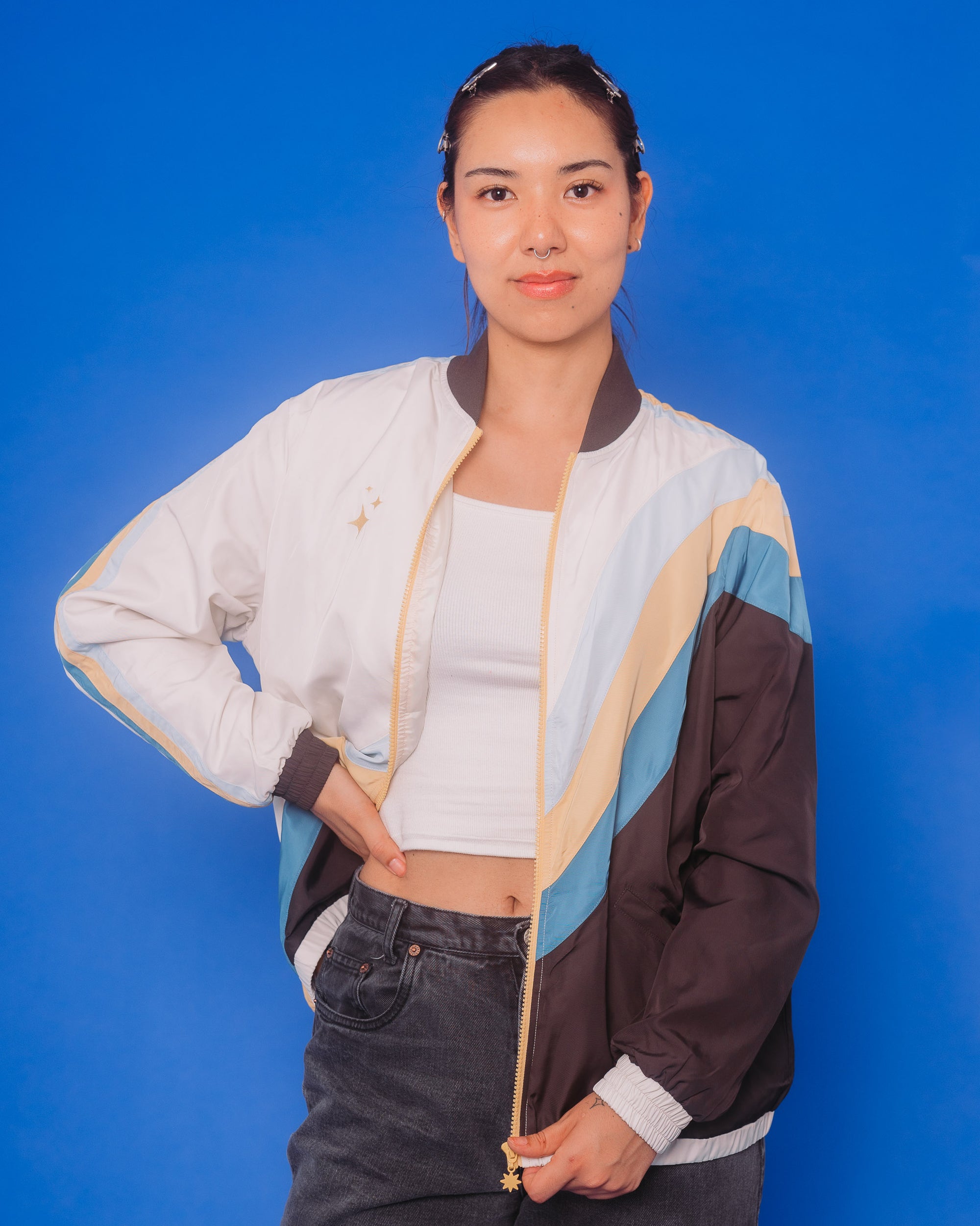 Woman wearing under the stars windbreaker in size medium in front of blue background.