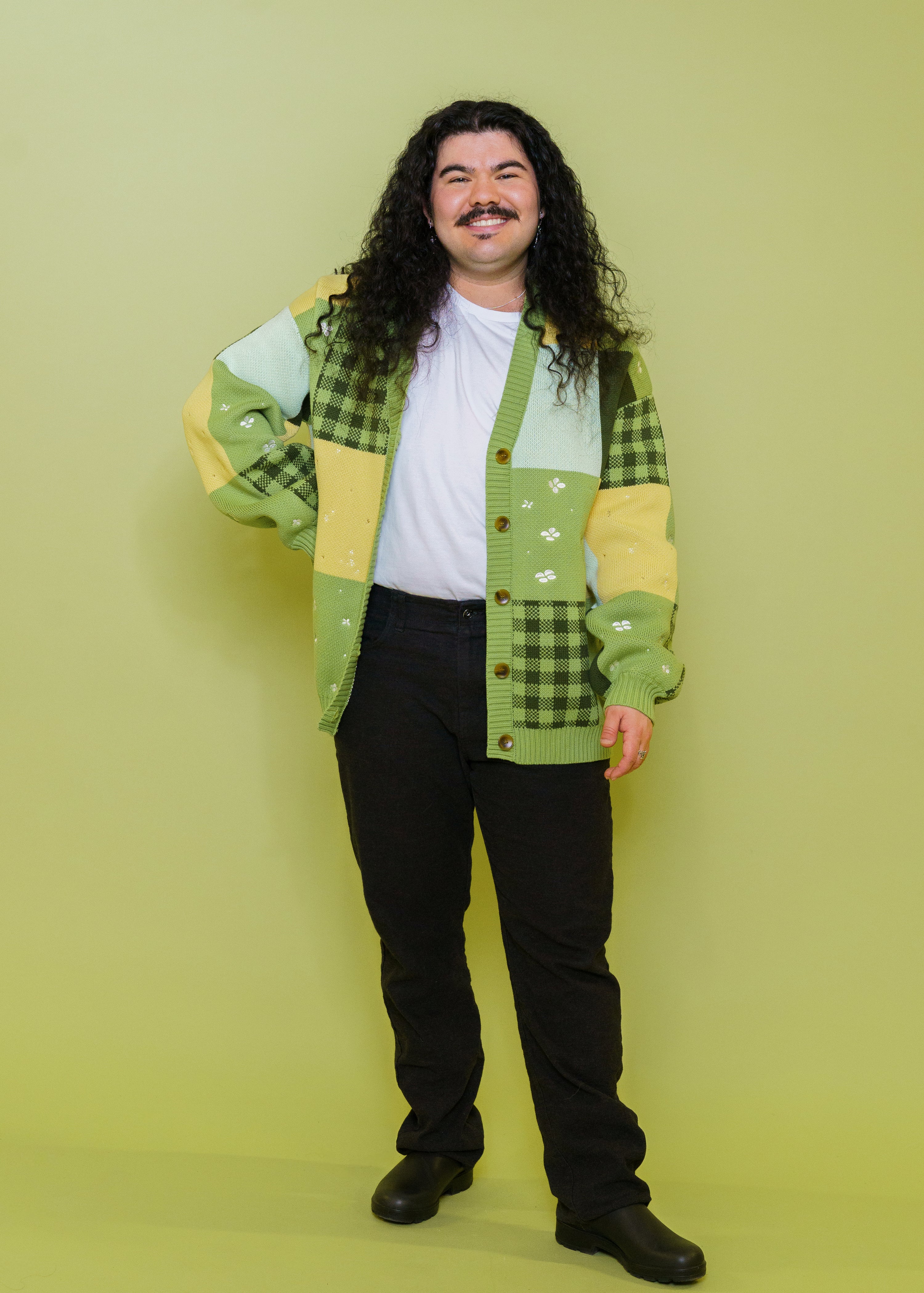 Man wearing Variety patchwork cardigan in size extra large in front of green background. 