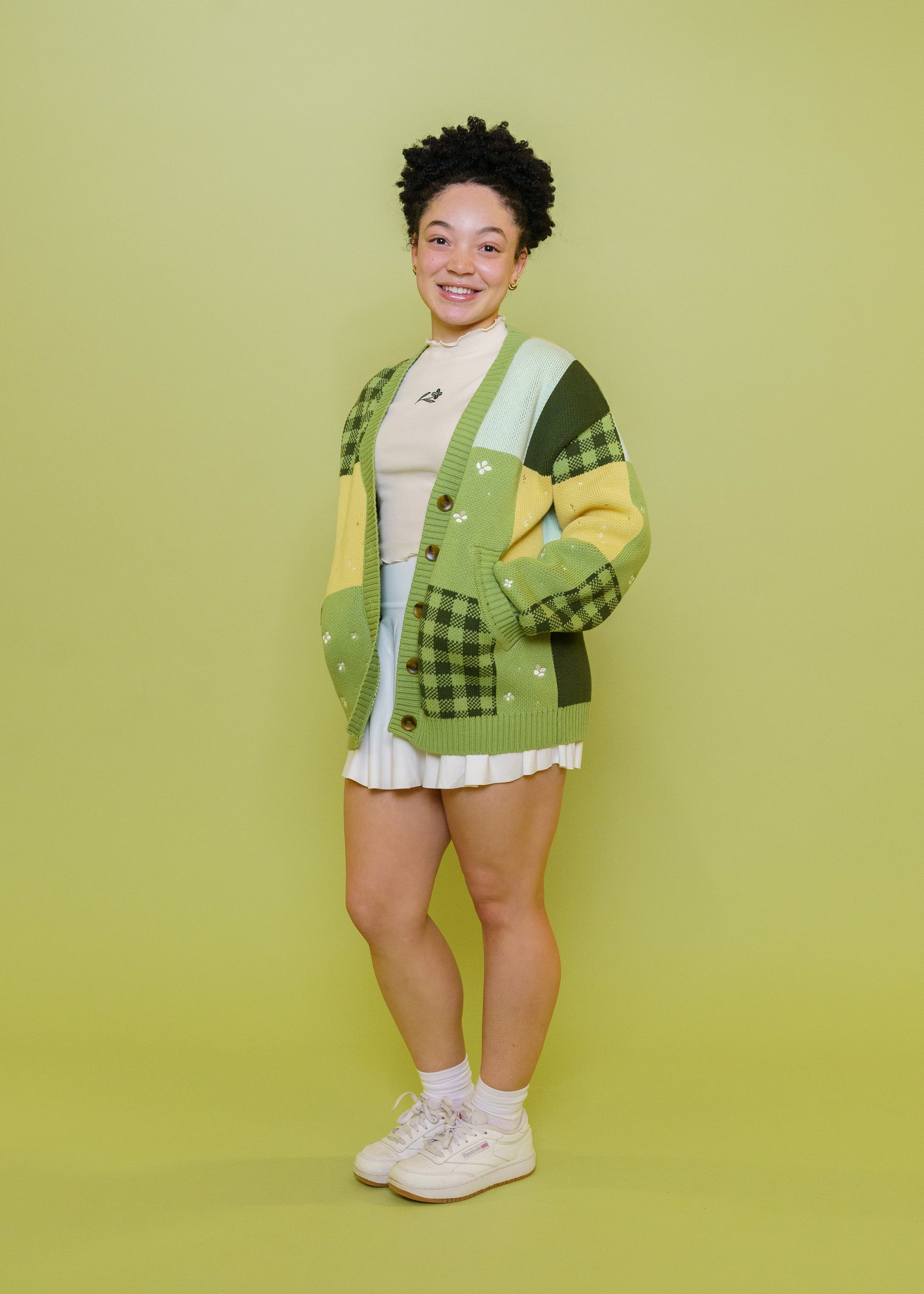 Woman wearing Variety patchwork cardigan in size extra small in front of green background.