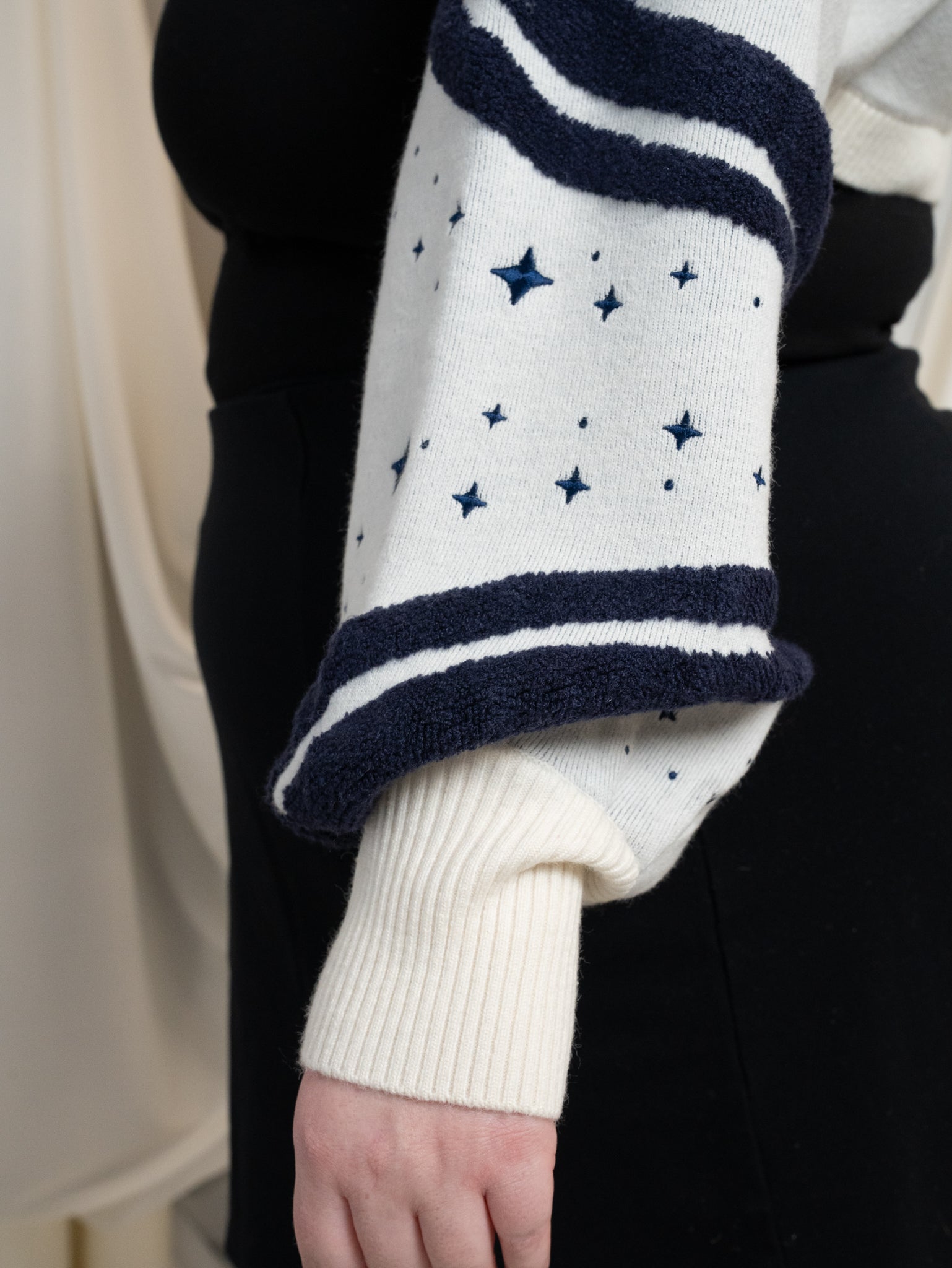 Close up of dark blue and white bolero sleeve showing the wavy dark blue details, dark blue embroidered sparkles and white cuff. 