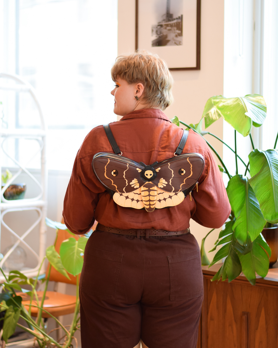 Model wearing death's head moth shaped bag as backpack.